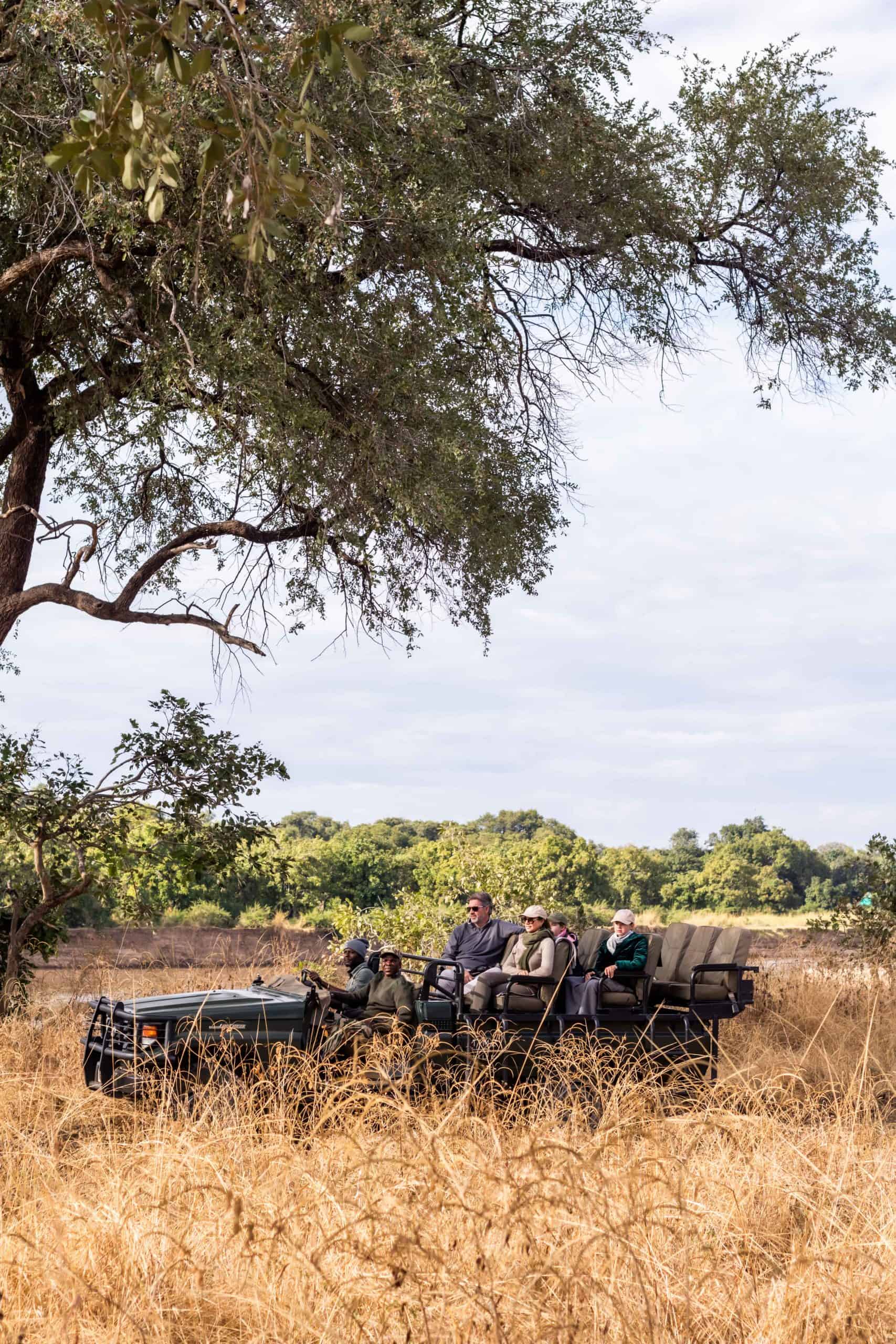A family of four with two guides on a game drive vehicle on safari in Zambia with Time + Tide