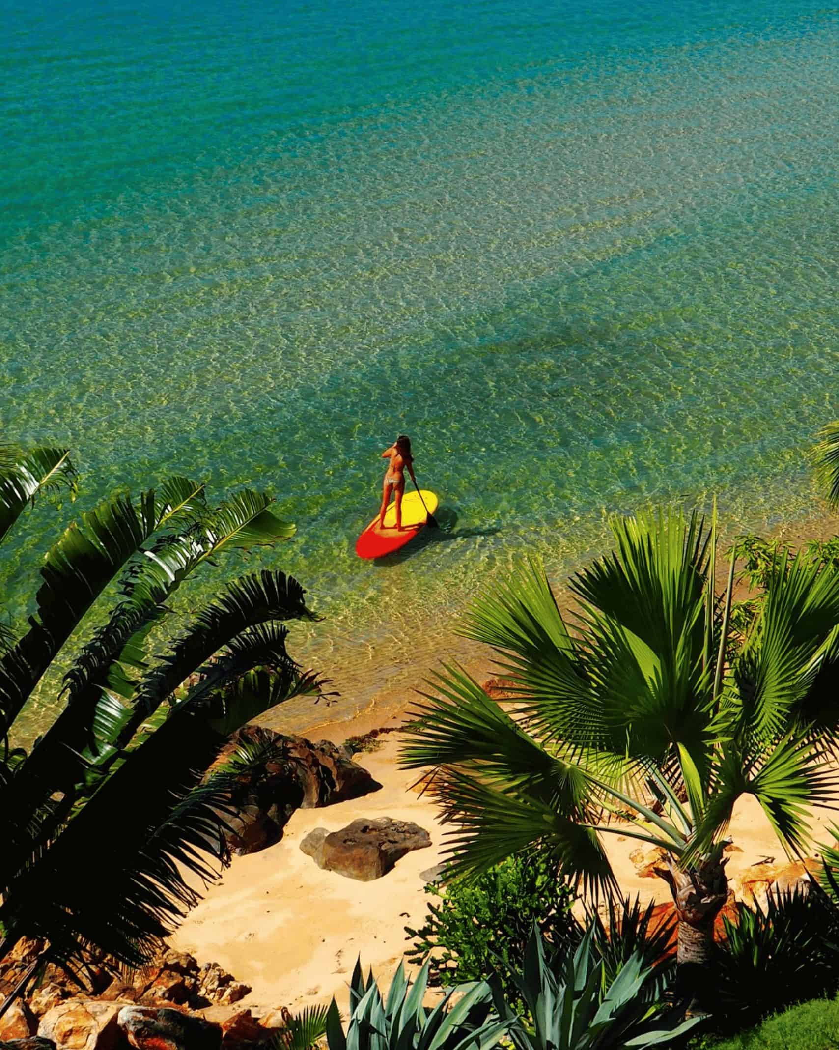 A woman on a stand up paddle board in the sea with Time + Tide Tsara Komba in Madagascar